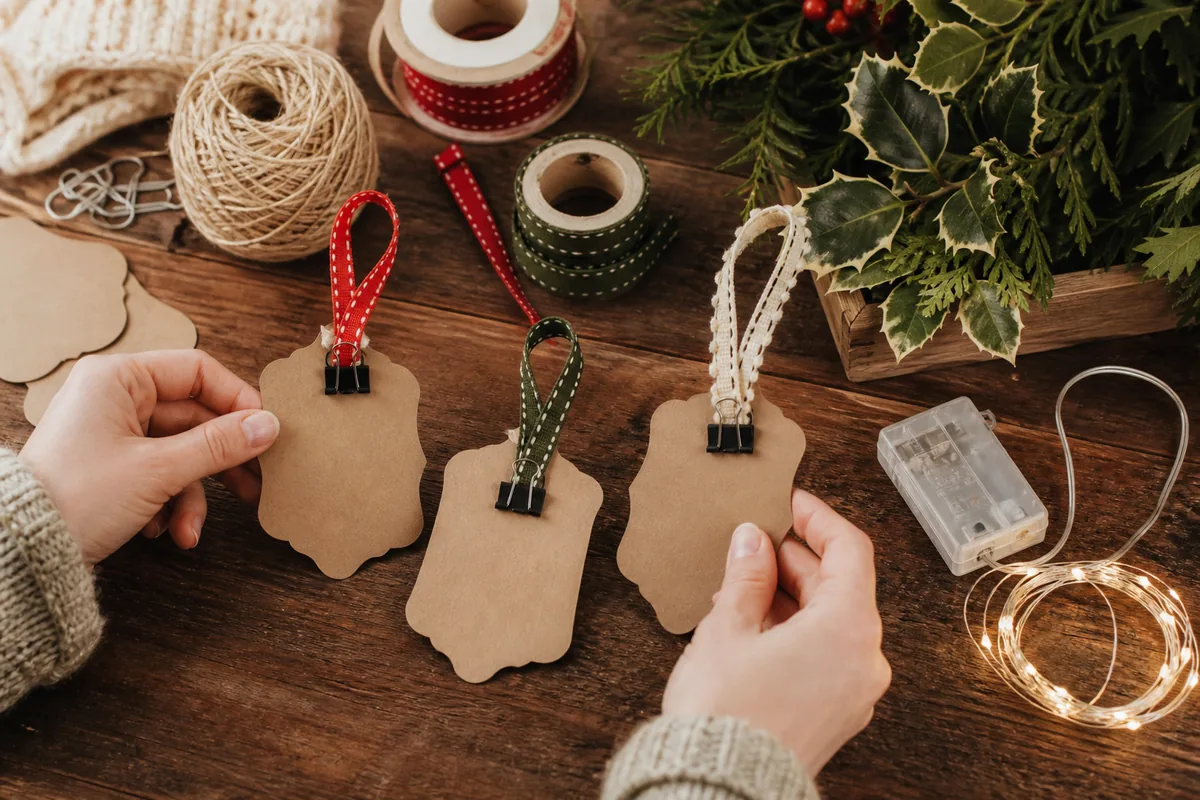 Paper hanging loops clipped while drying beside ribbon, twine, greenery, and battery lights